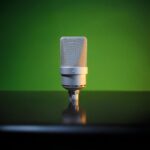 Close-up of a studio microphone with green backdrop, ideal for podcasting or music recording visuals.